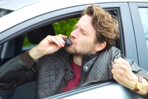 Hezký šťastný muž v autě líbání klíč nové auto — Stock fotografie