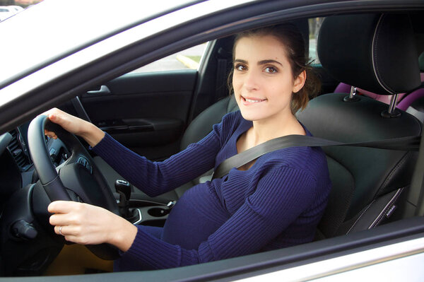 Beautiful pregnant woman sitting in car driving smiling looking camera