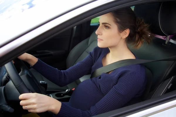 Mujer embarazada serio conducir coche sosteniendo rueda —  Fotos de Stock