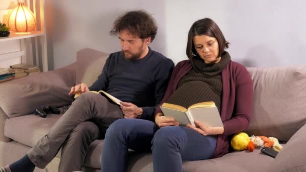 Hamile Çift Kanepede Kitap Okuyarak Rahatlıyor — Stok video
