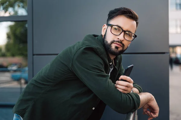 Homem em óculos segurando smartphone — Fotografia de Stock