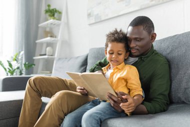 father and son reading book together clipart