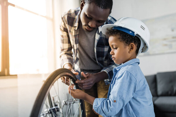 afro father and son repairing bicycle