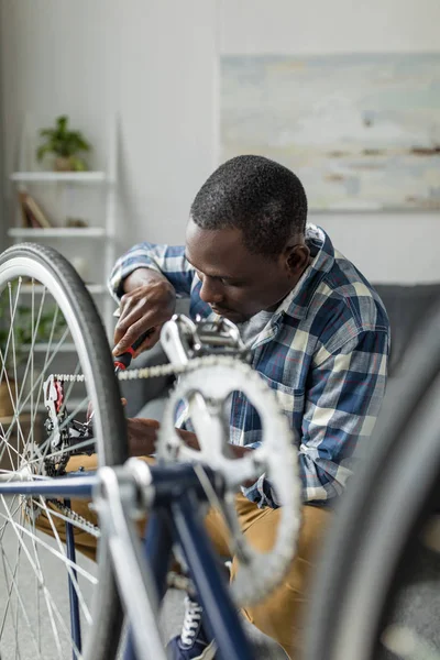 Afro man repairing bicycle at home — Stock Photo, Image