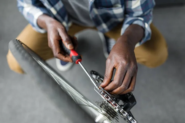 Afro man repairing bicycle at home — Free Stock Photo