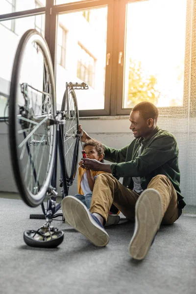 Afro father and son repairing bicycle — Stock Photo, Image