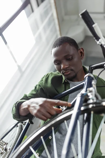 Afro man repairing bicycle at home — Free Stock Photo