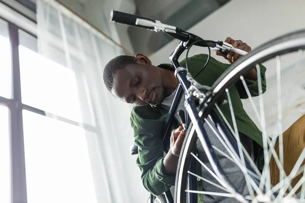 Afro homem reparação de bicicleta em casa — Fotos gratuitas