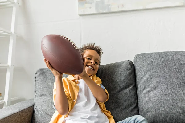 Afro menino com bola de futebol americano — Fotografia de Stock