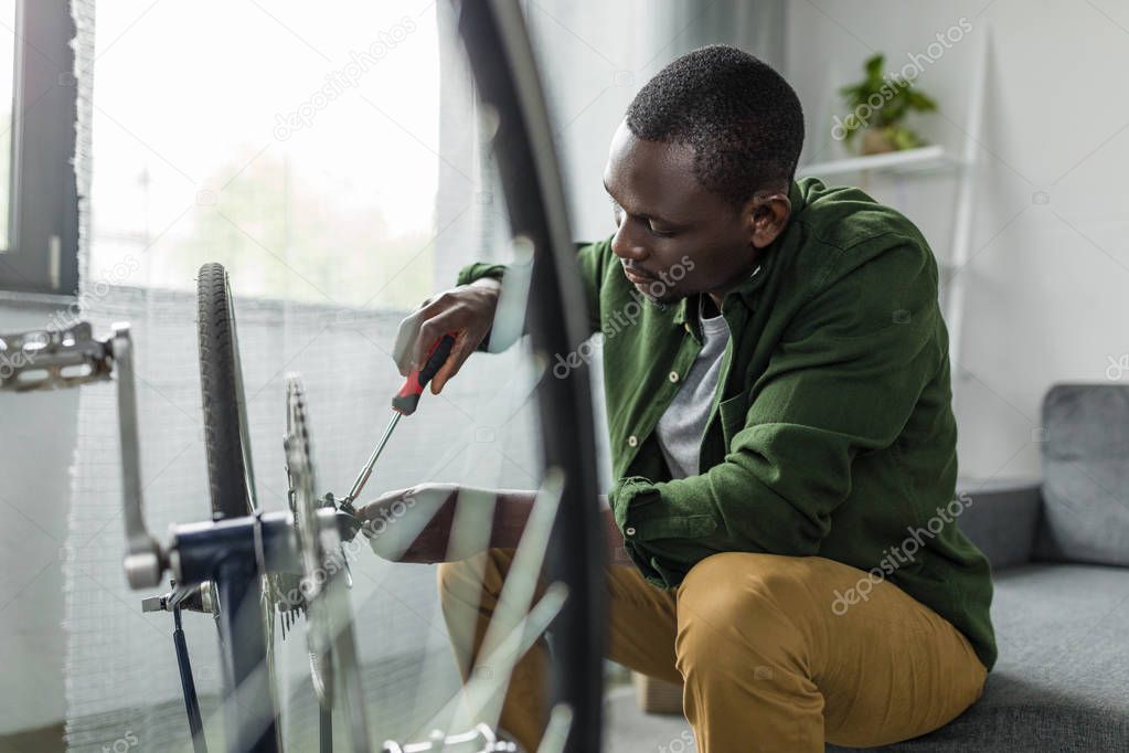 afro man repairing bicycle at home