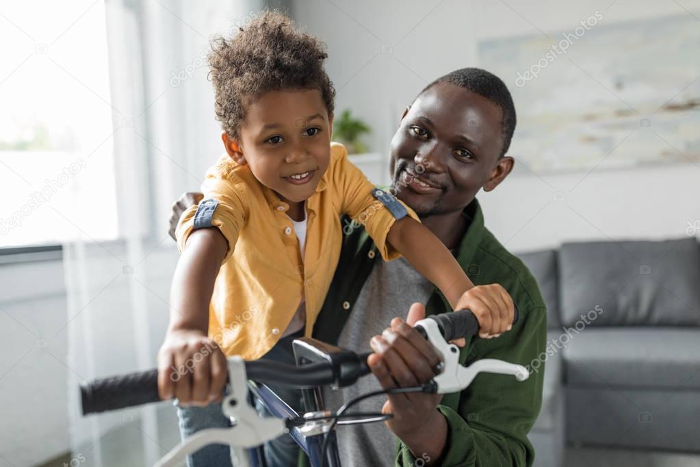 father and son playing with bicycle at home