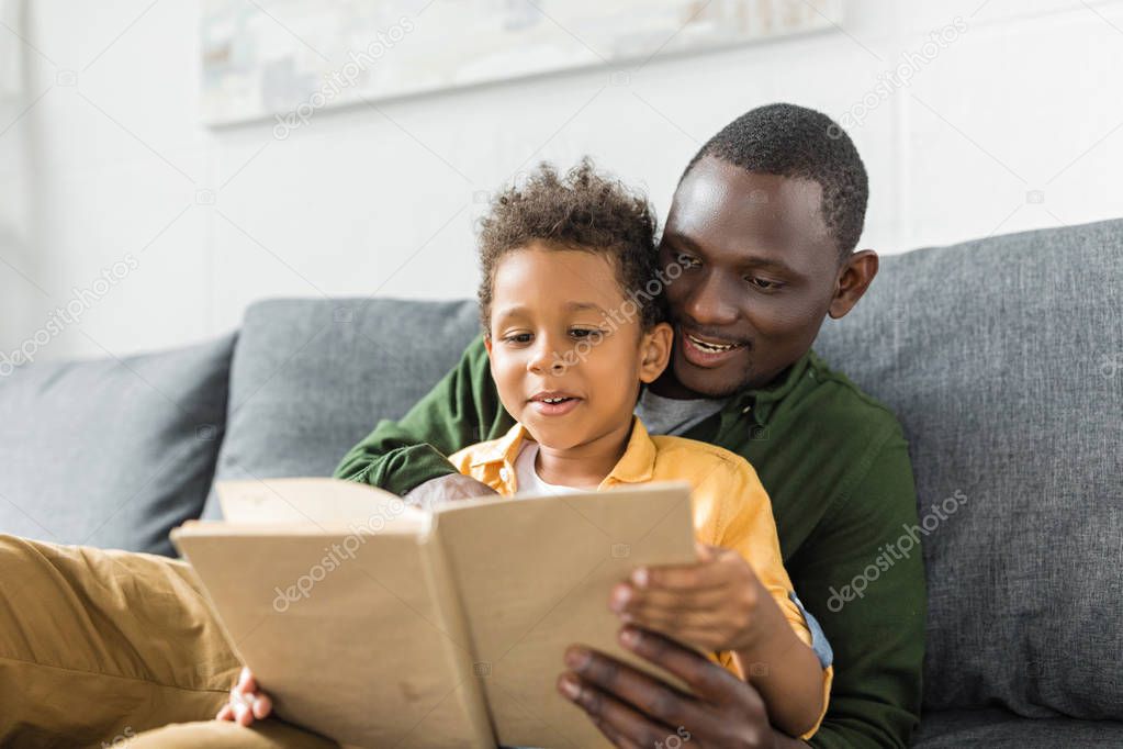 father and son reading book together