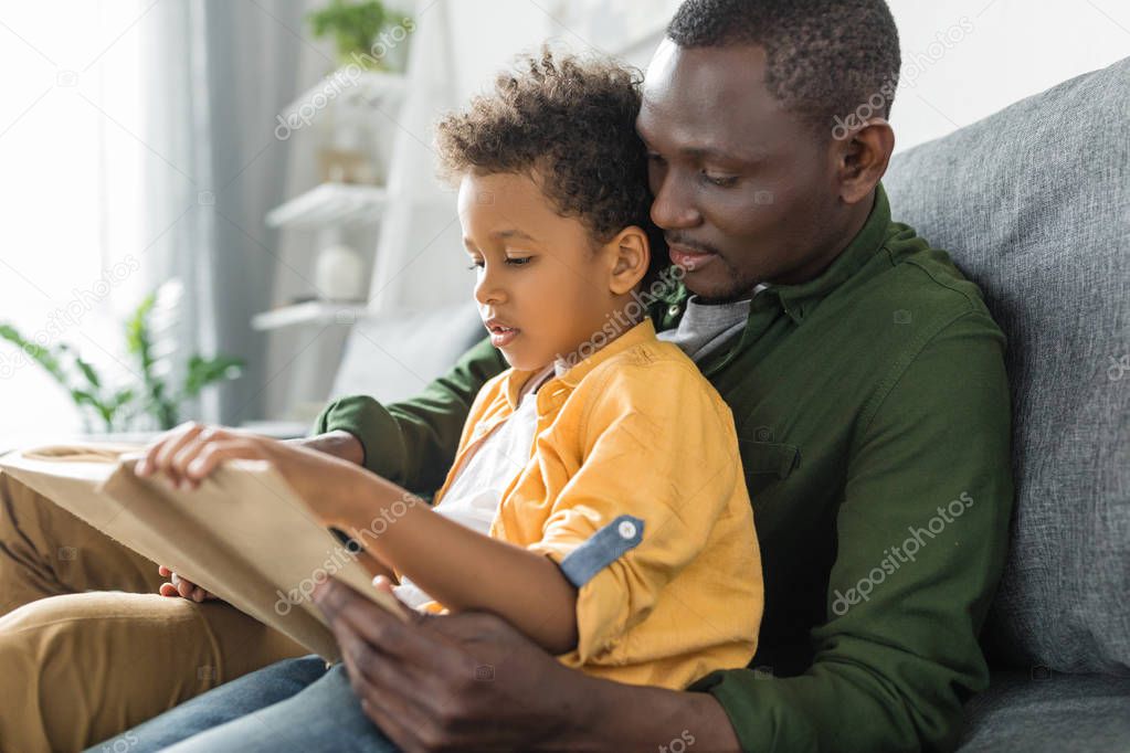 father and son reading book together