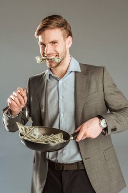 Genç işadamı banknot para içinde kızartma ağız ile pan izole üzerinde gri