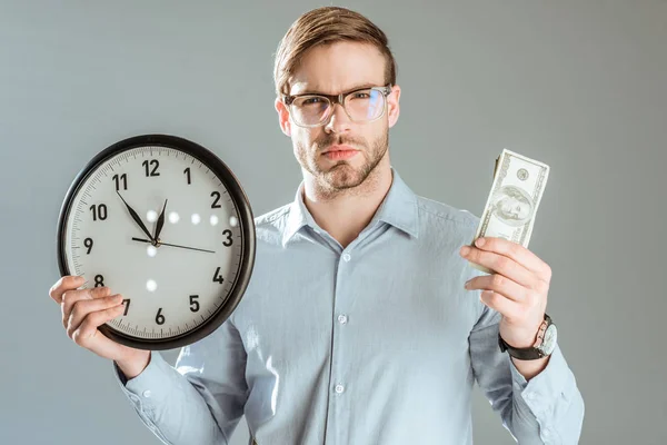 Nachdenklicher Geschäftsmann Zeigt Geld Und Uhr Isoliert Auf Grau — Stockfoto