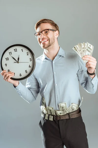 Junger Lächelnder Geschäftsmann Zeigt Geld Und Uhr Isoliert Auf Grau — Stockfoto