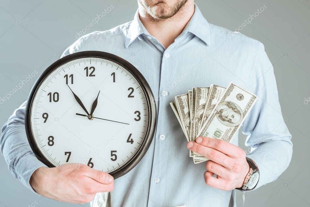 Close-up view of businessman showing money and clock isolated on grey