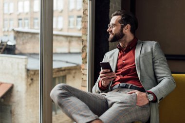 smartphone kullanarak ve penceresine bakarak gözlük gülümseyen yakışıklı