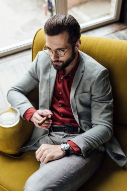 Kendine güvenen zarif adam puro ve kanepede oturan kül tablası 