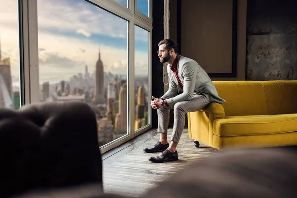 在窗口与城市视野的时尚西装的沉思优雅男子 — 图库照片