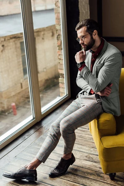 ウィンドウで座っている流行のスーツの思慮深い男 — ストック写真