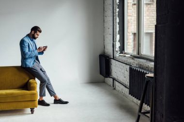 mavi elbiseli sarı kanepe smartphone kullanarak moda adam 