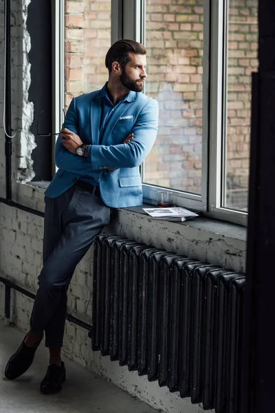 thoughtful handsome man in blue trendy suit looking at window