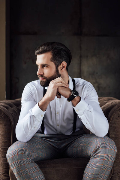 handsome stylish thoughtful man sitting in armchair 