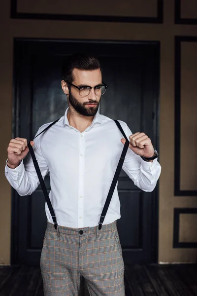 Elegante Uomo Alla Moda Posa Camicia Bianca Bretelle Contro Porta — Foto Stock