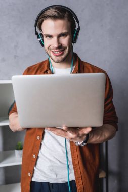 yakışıklı delikanlı laptop ile çalışma ve kameraya bakarak kulaklık