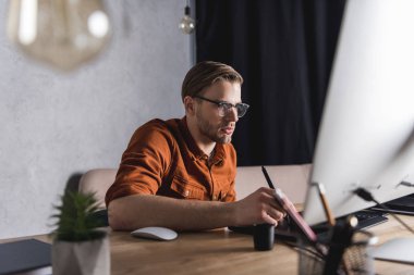 stylish young designer working with drawing tablet at workplace clipart