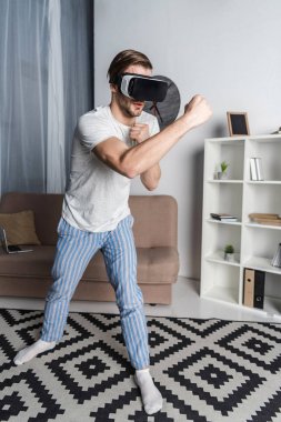 sanal gerçeklik kulaklık ve pijama dövüş oyunu oynayan genç adam