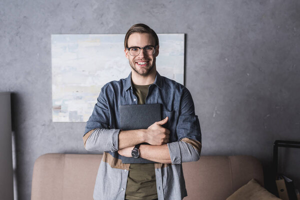 happy young man in eyeglasses holding book