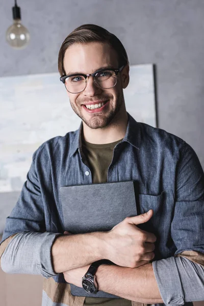 Joven Sonriente Con Anteojos Sosteniendo Libro —  Fotos de Stock