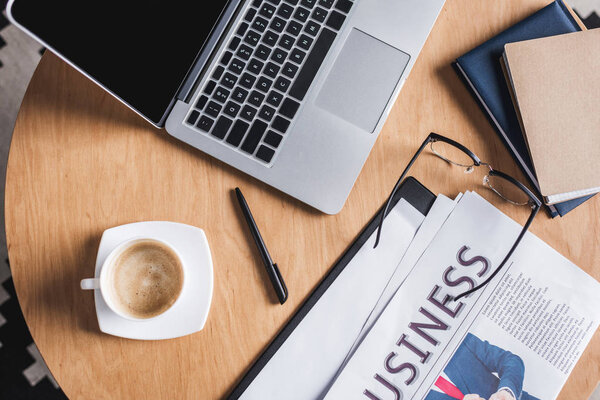 вид на рабочее место с ноутбуком и газетой
