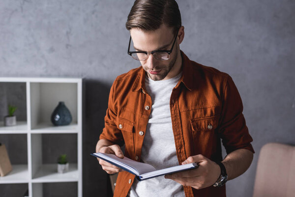 handsome young man in eyeglasses reading book