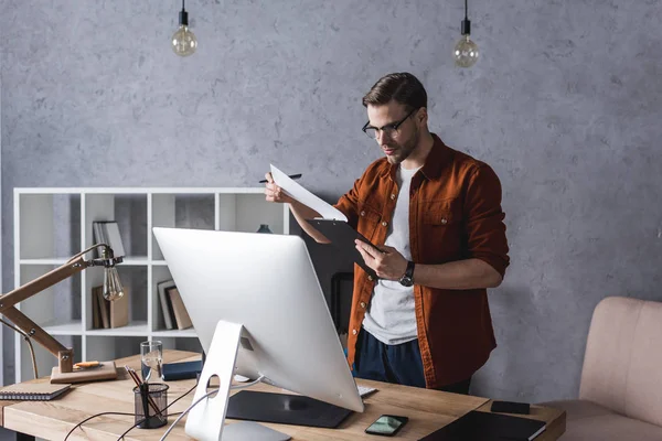 Serious Young Businessman Clipboard Standing Workplace — Stock Photo, Image