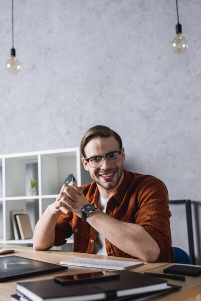 happy young designer sitting at workplace in modern office