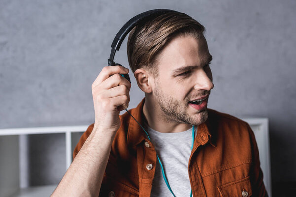 young man taking off one headphone to ask question