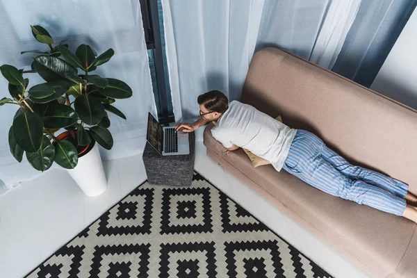 Hoge Hoekmening Van Freelancer Pyjama Werken Met Laptop Bank — Gratis stockfoto