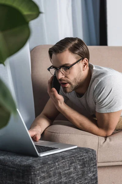 Jovem Freelancer Trabalhando Com Laptop Conversando Por Telefone Sofá Imagem De Stock