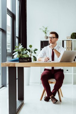 evrak ve modern ofis içinde laptop ile şık düşünceli işadamı