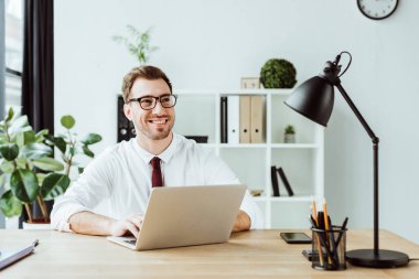 laptop ile modern ofis işyerinde çalışan işadamı gülümseyen