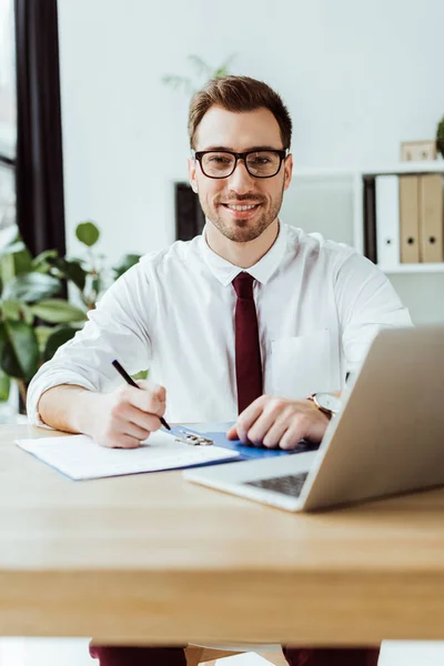Handsome Smiling Businessman Writing Documents Workspace Laptop — Stock Photo, Image
