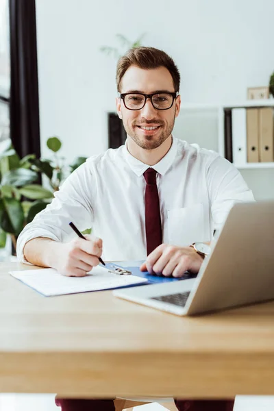 Guapo Sonriente Hombre Negocios Escribiendo Documentos Espacio Trabajo Con Ordenador —  Fotos de Stock