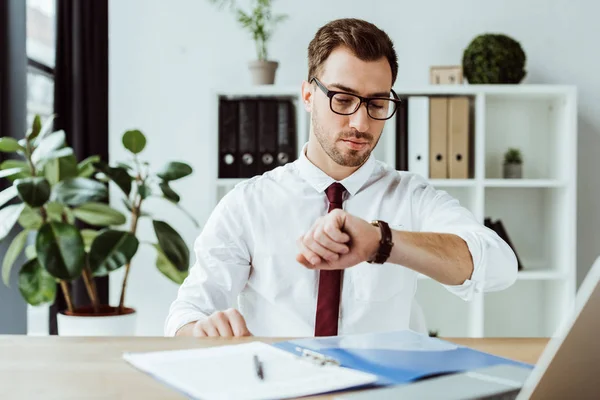 Hombre Negocios Guapo Mirando Reloj Pulsera Mientras Está Sentado Mesa — Foto de Stock