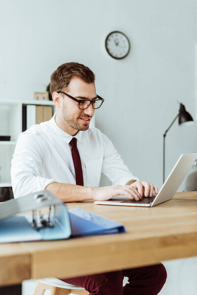 handsome businessman working with laptop at workplace with documents