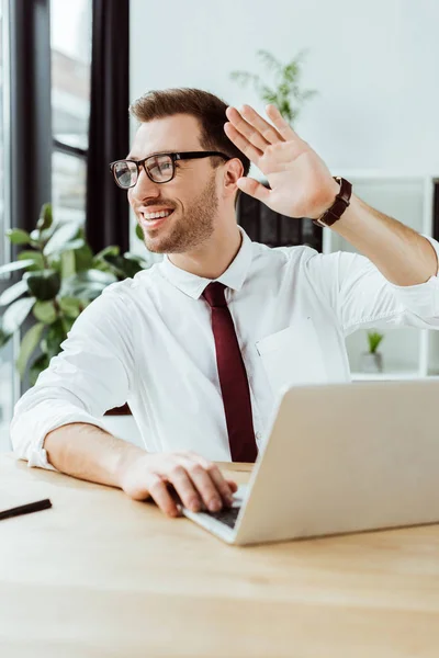 Homem Negócios Sorrindo Trabalhando Com Laptop Local Trabalho Acenando Para — Fotos gratuitas