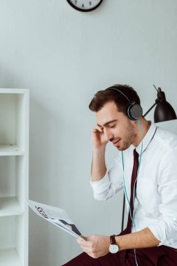 kulaklıklar müzik dinleme ve gazete okuyan genç işadamı