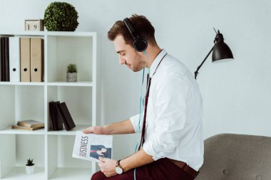 kulaklıklar müzik dinleme ve gazete okuma yakışıklı işadamı